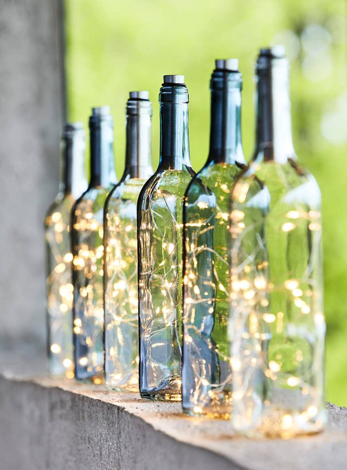 Six glass bottle lanterns sitting in a row 