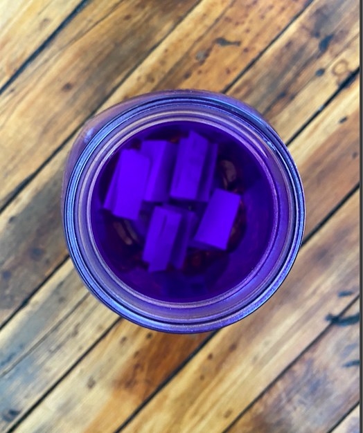 A mason jar with pieces of folded up paper in it is photographed from above. 