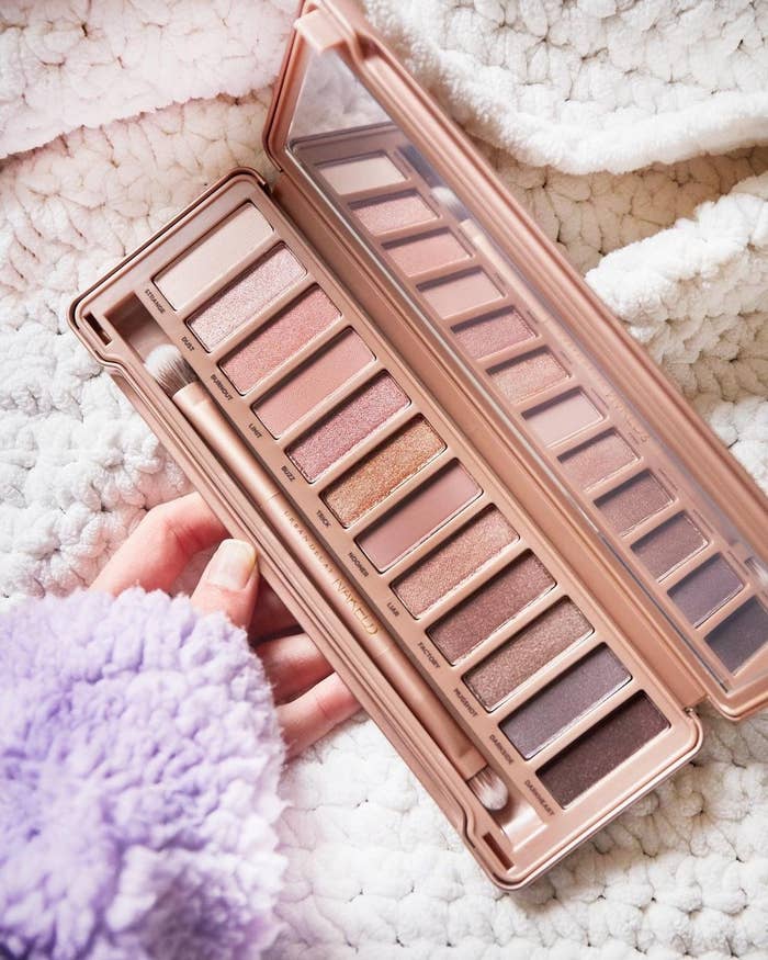 A person holding an open eyeshadow palette