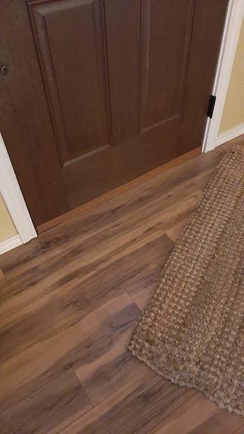 a reviewer photo of the door draft stopper in brown against a door