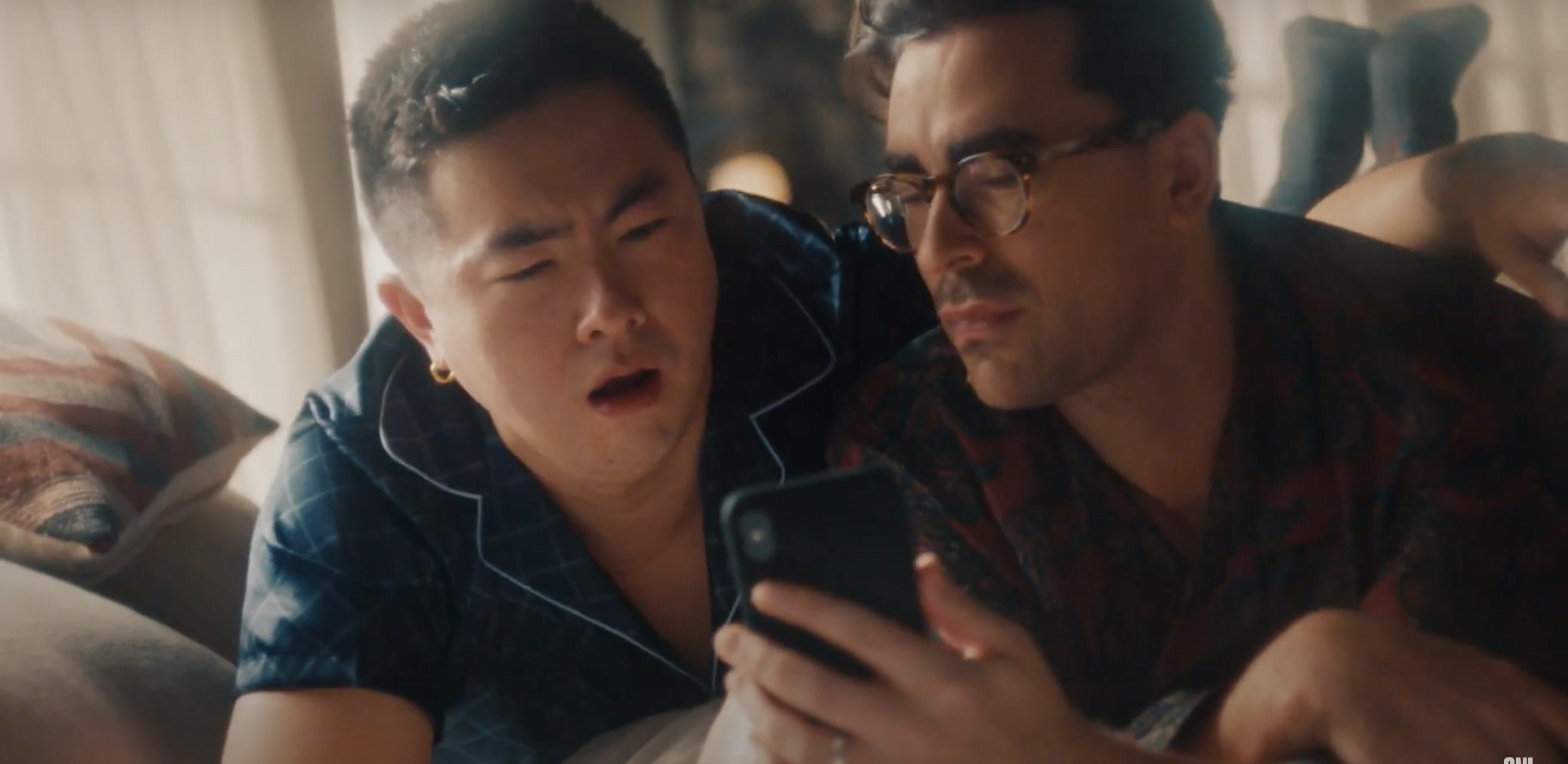 Two men look excited while browsing Zillow on their phone