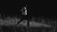 A man kicks and screams in a field at night. 