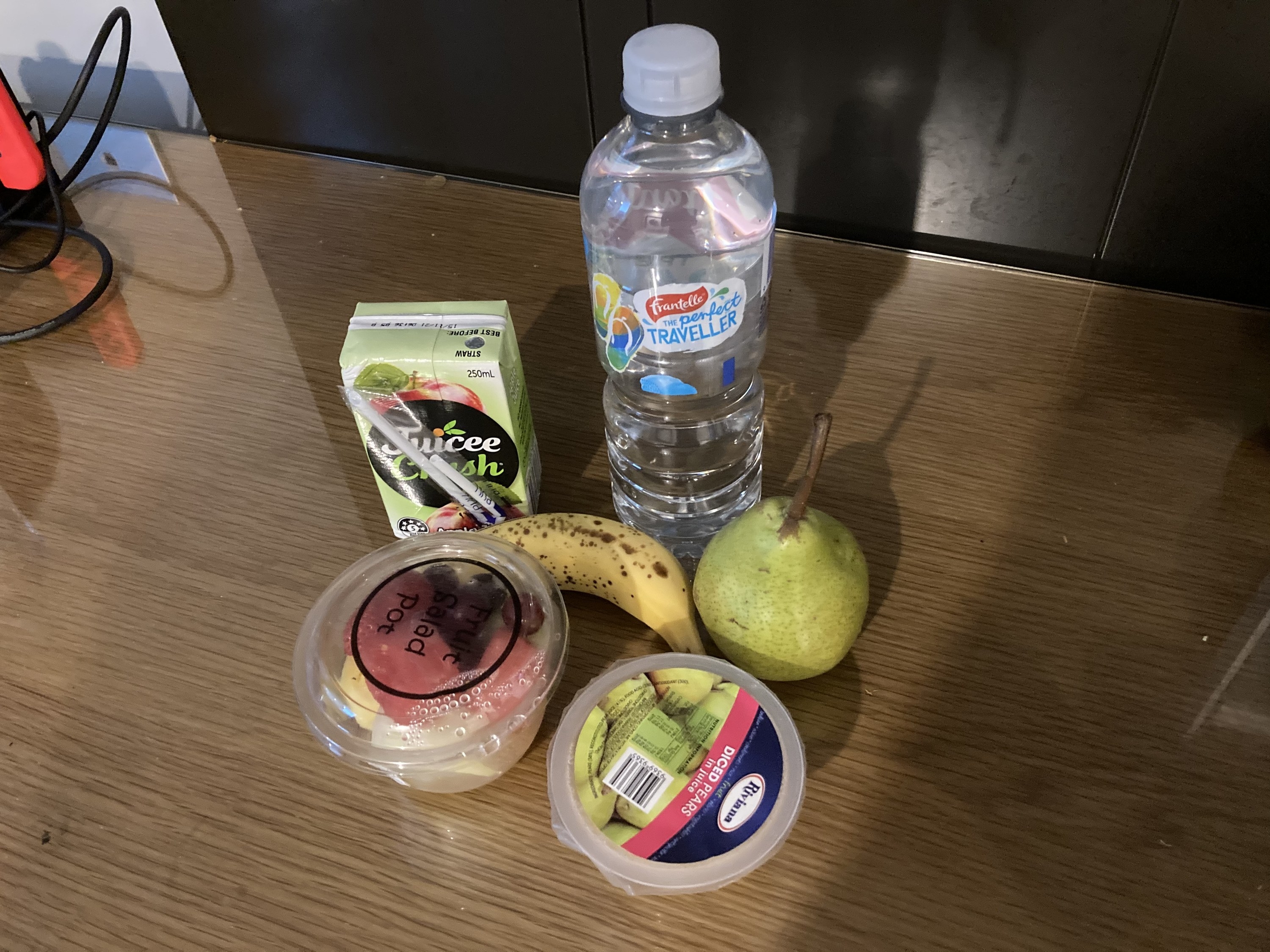 A breakfast which has two small fruit containers, a juice box and a banana