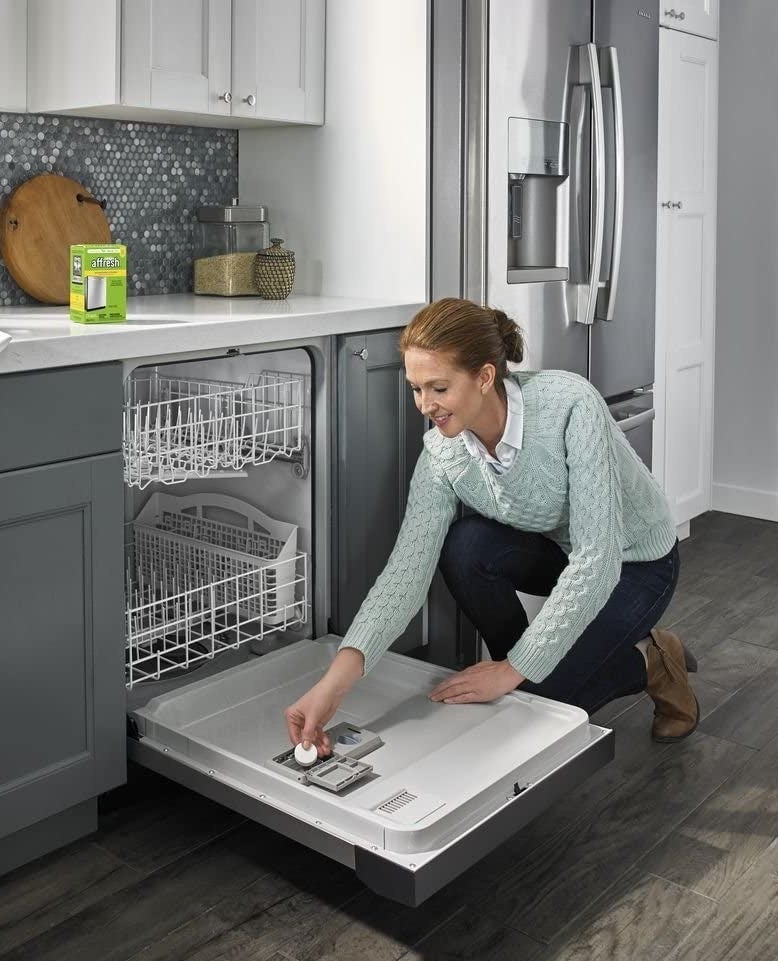 a person putting the dishwasher cleaner tablet into the dishwasher