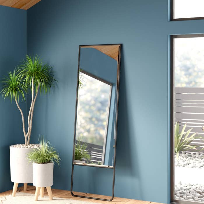 black framed wall mirror leaning against a blue wall