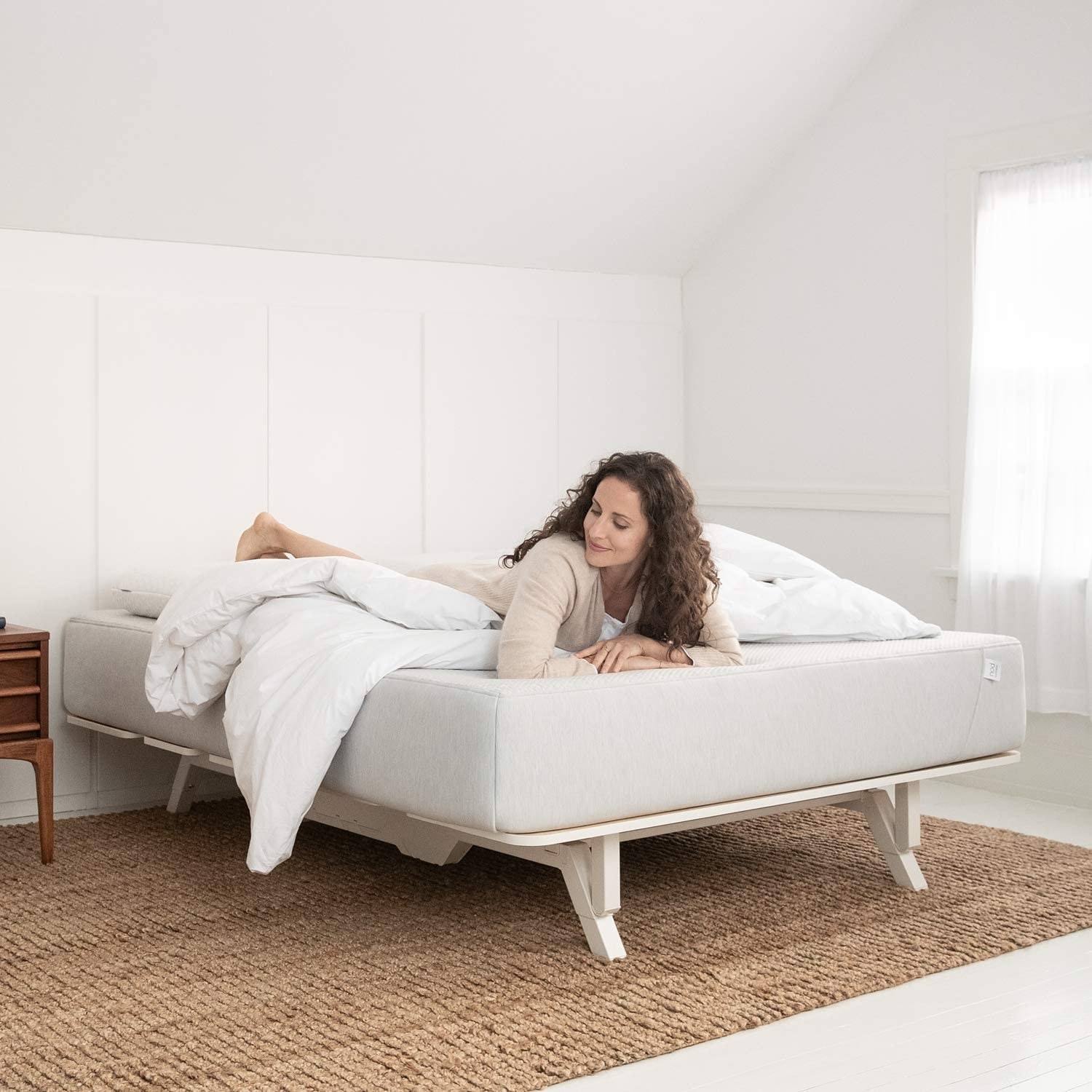 model lounges on Tuft &amp;amp; Needle white adaptive foam mattress on a bed