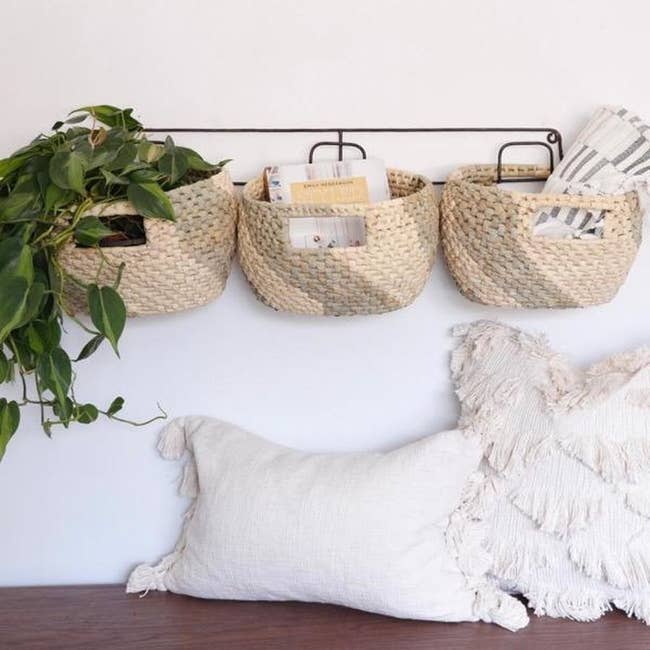 The three beige baskets hanging from the wall-mounted metal frame