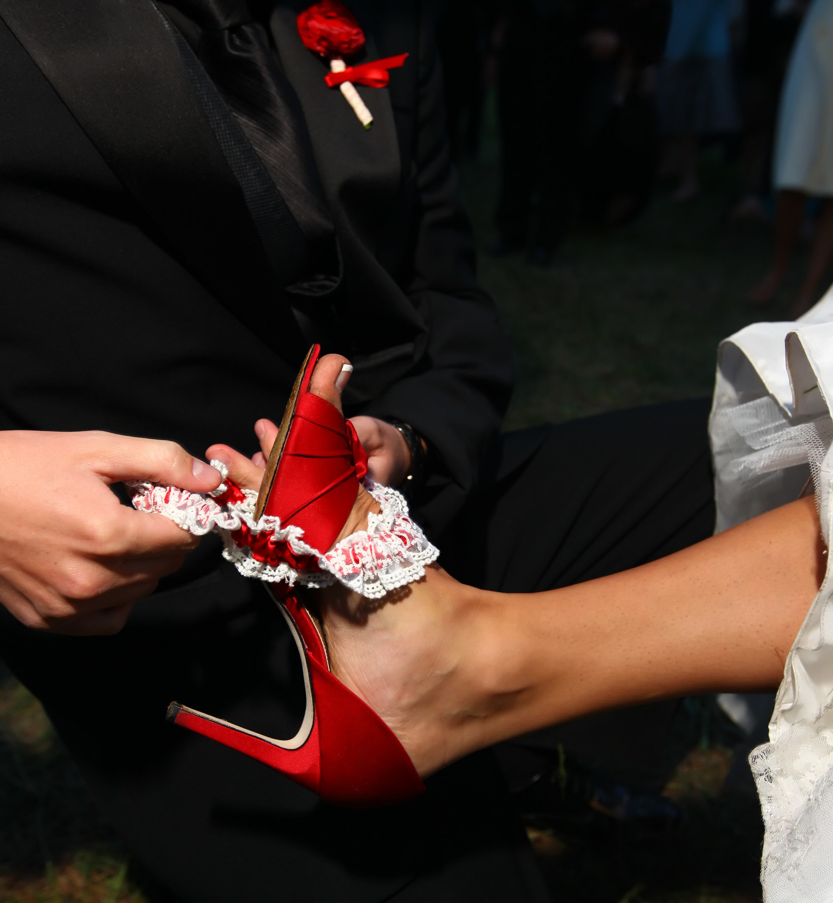 A groom slides a garter off his bride&#x27;s ankle