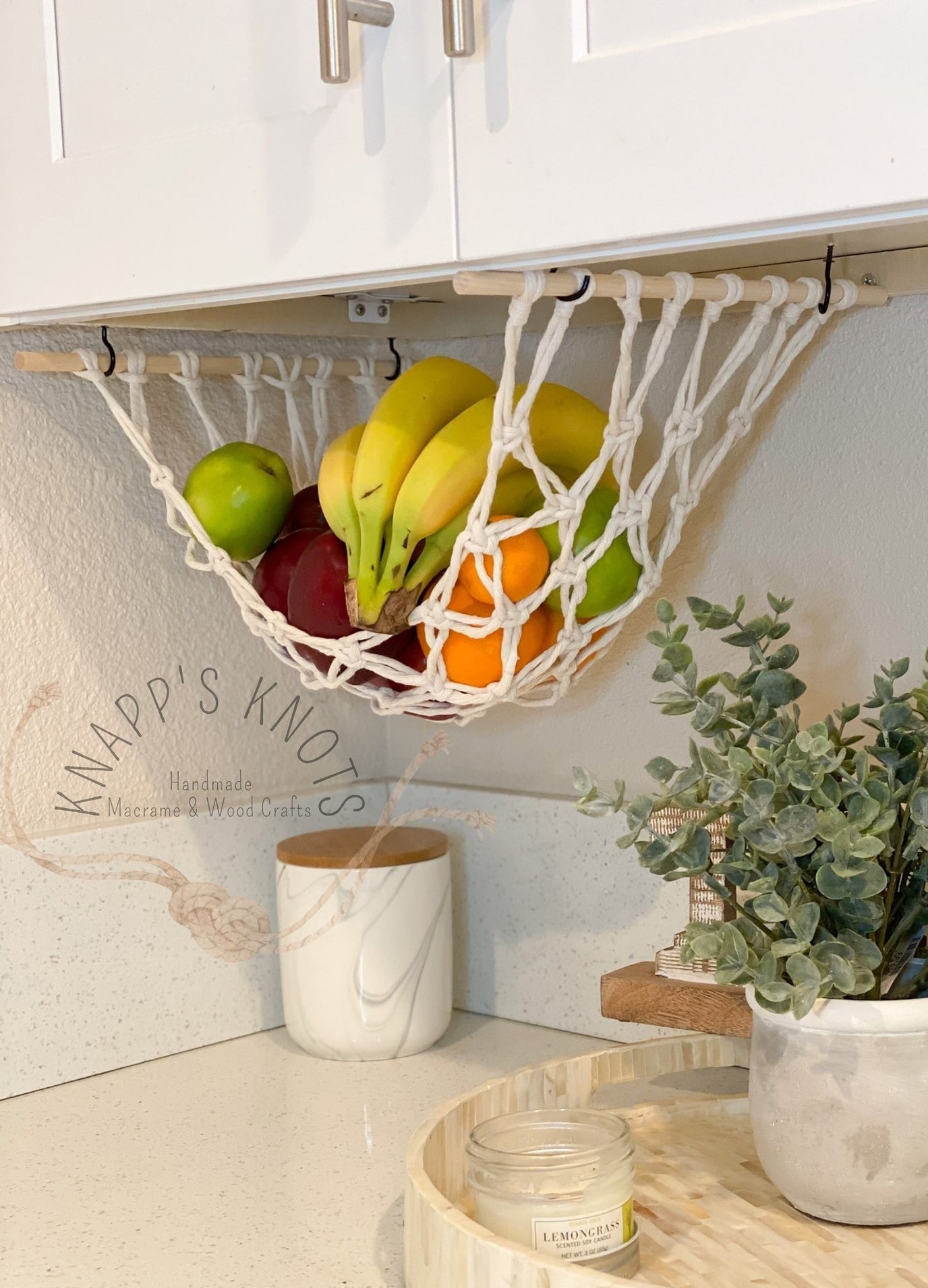 The macrame net hung below a cabinet with wood dowels and hooks