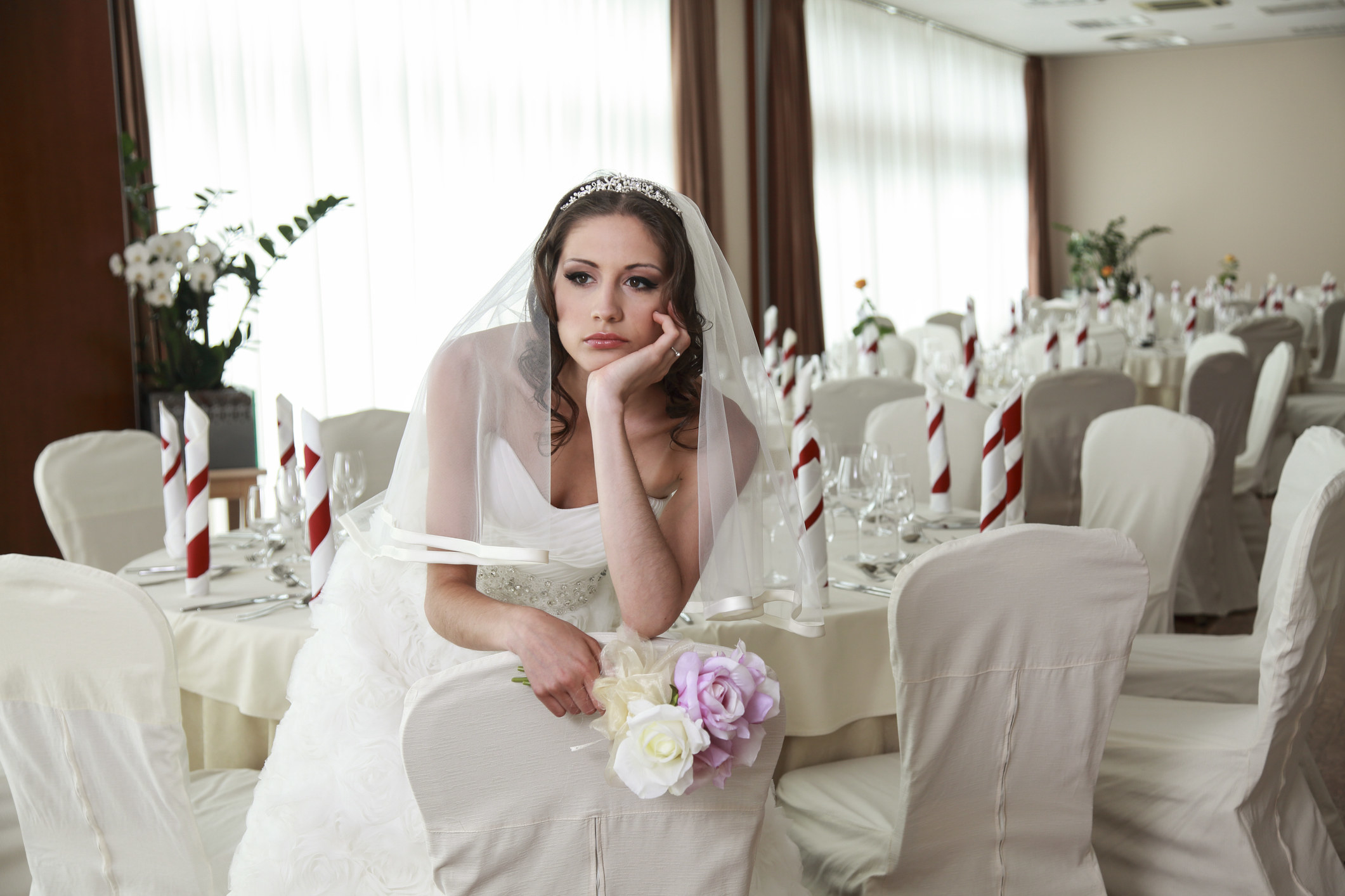 A disappointed bride sits alone at her wedding