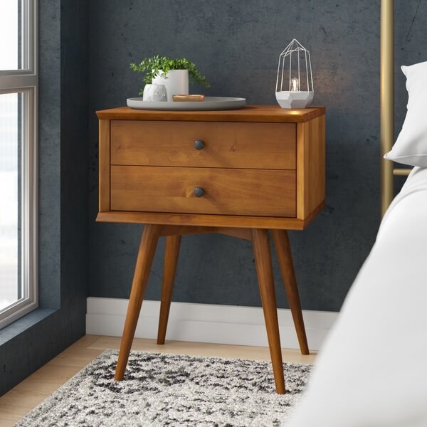 The wooden nightstand with four tapered legs