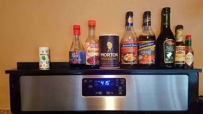 A reviewer's photo of the black shelf holding various pantry items like soy sauce and tabasco