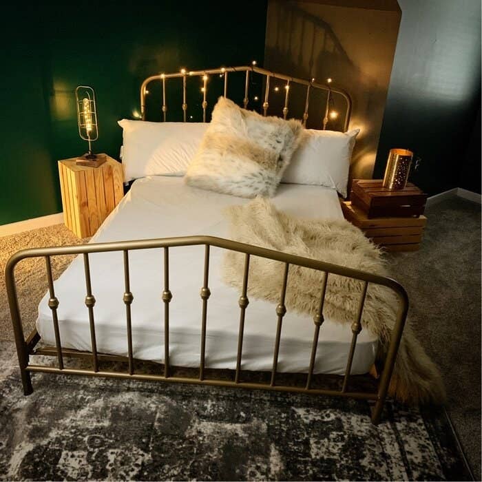 gold bed frame in a room with lights all around it