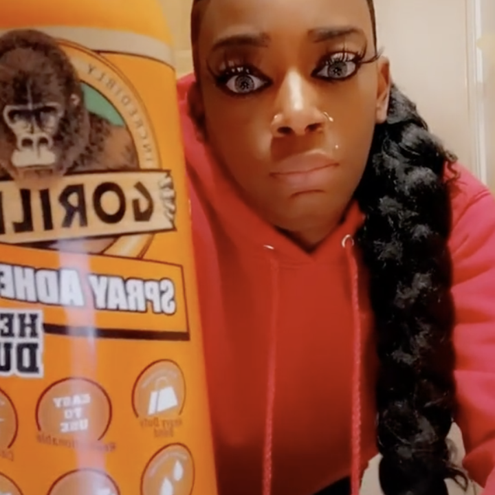 The woman holds up a spray can of Gorilla Glue toward the camera