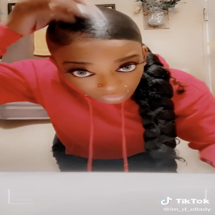 A woman motions to the camera that her hair is glued flat to her scalp