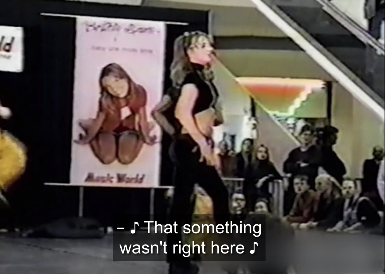 Archived footage of Britney Spears performing "...Baby One More Time" in a mall