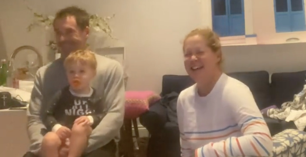 Amy Schumer laughs with her husband and son while watching the Super Bowl