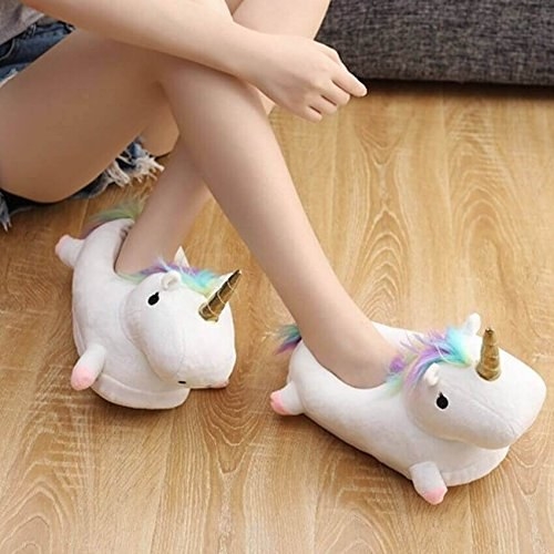 A person wearing a pair of unicorn slippers