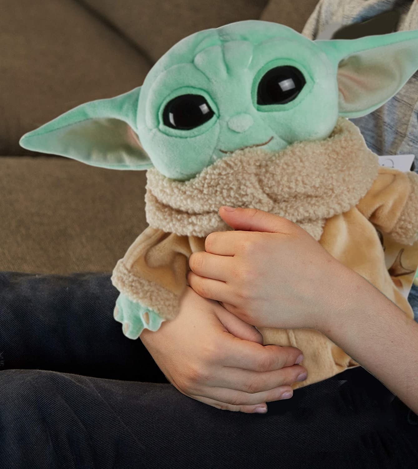 A hand holding A Baby Yoda plushie 