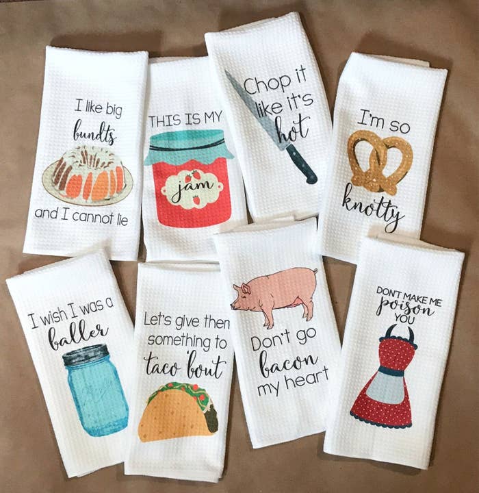 eight kitchen towels that are white wiht one colorful item on it and a quote. ONe says &quot;Let&#x27;s give them something to taco &#x27;bout&quot; with a taco underneath