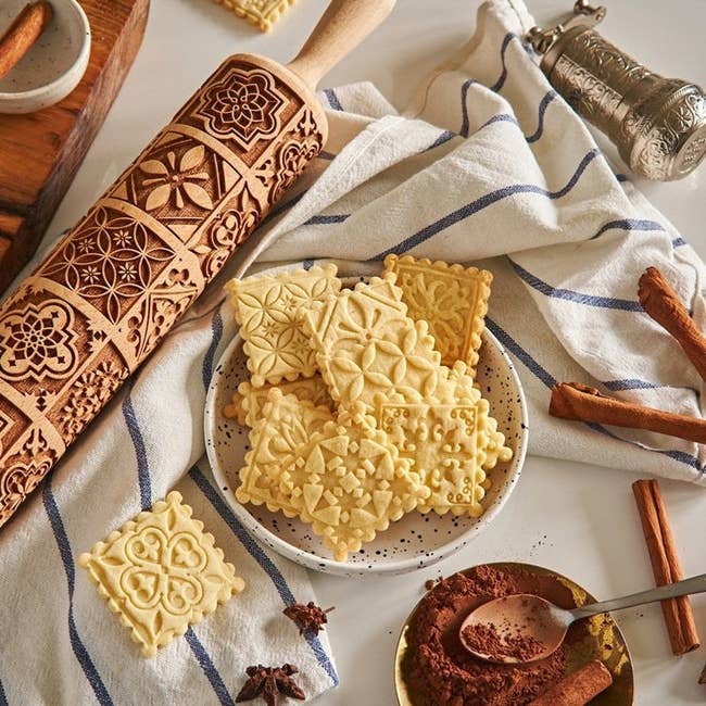the wooden rolling pin with embossment designs engraved in it to impress upon the cookies and cookies in a bowl with designs on them from the pin