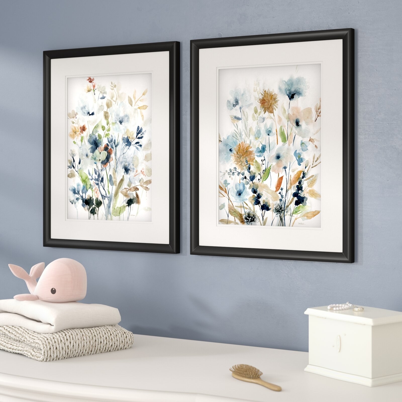 two floral prints in black frames that are hanging on a blue wall