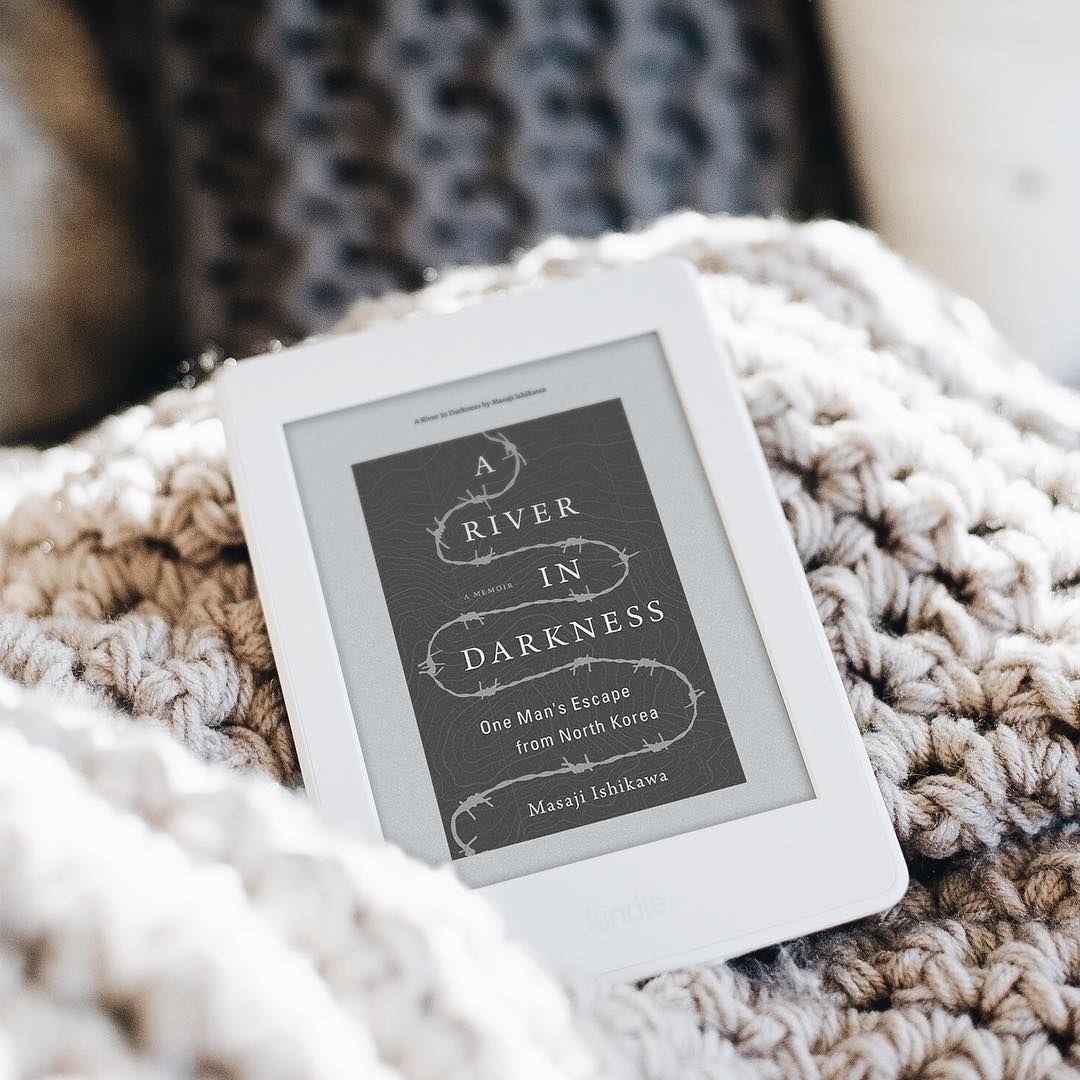 A Kindle Paperwhite on a cozy knit blanket 