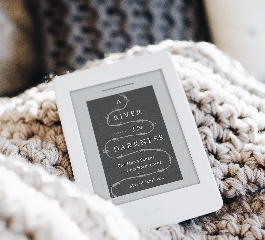 A Kindle Paperwhite on a cozy knit blanket 