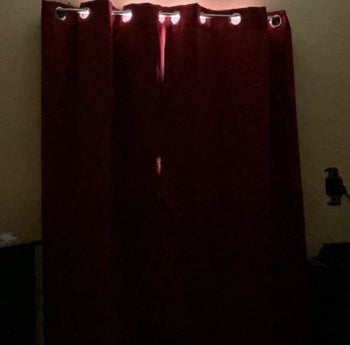 sunblock curtains closed with tiny peaks of light at the top to show that its daytime but the room is dark showing that the curtains work to block the light