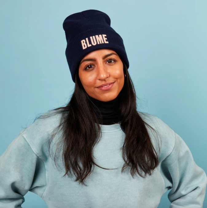 A smiling person wearing the branded toque while looking into the camera