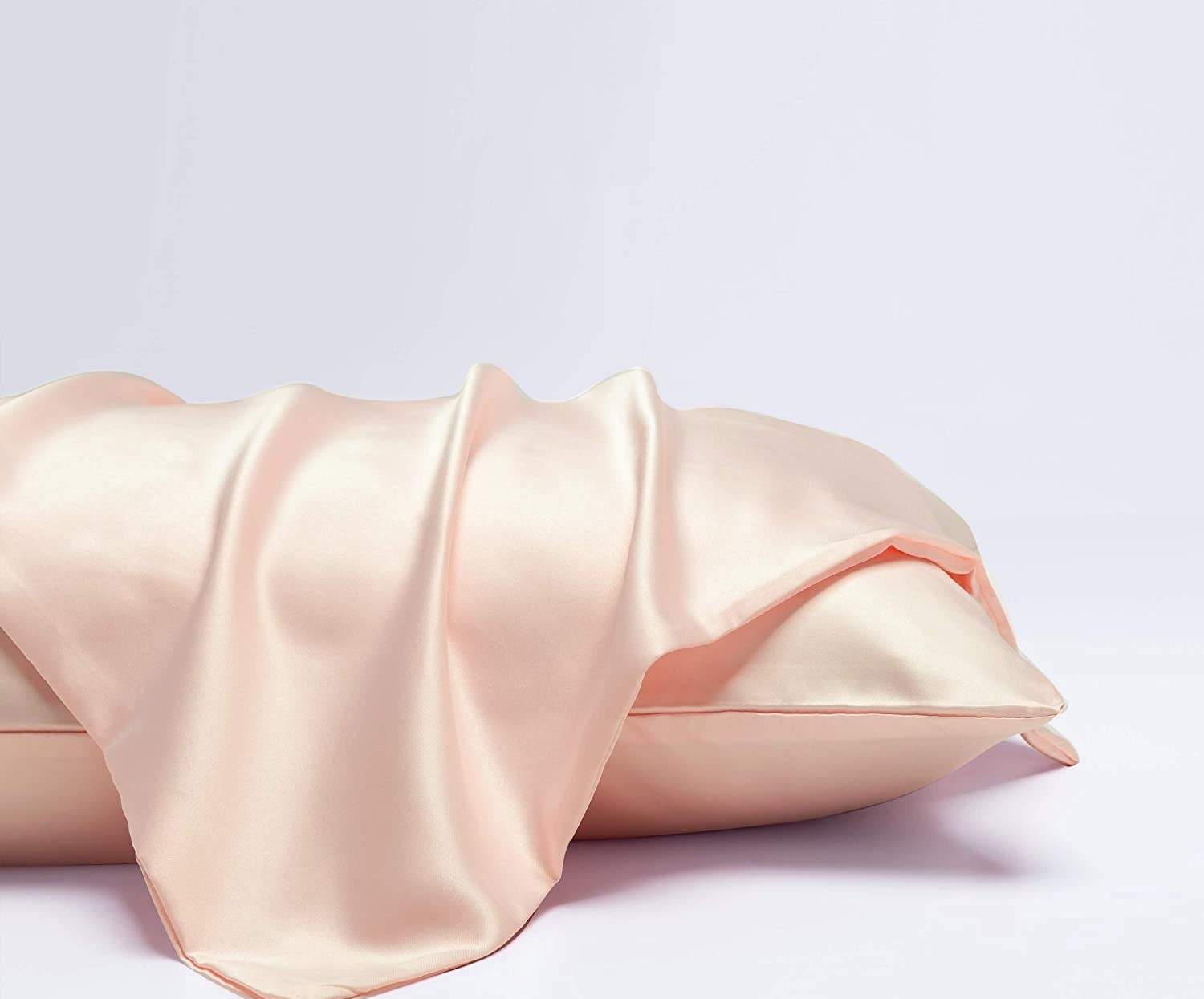 The light pink pillowcase laying on a dressed pillow