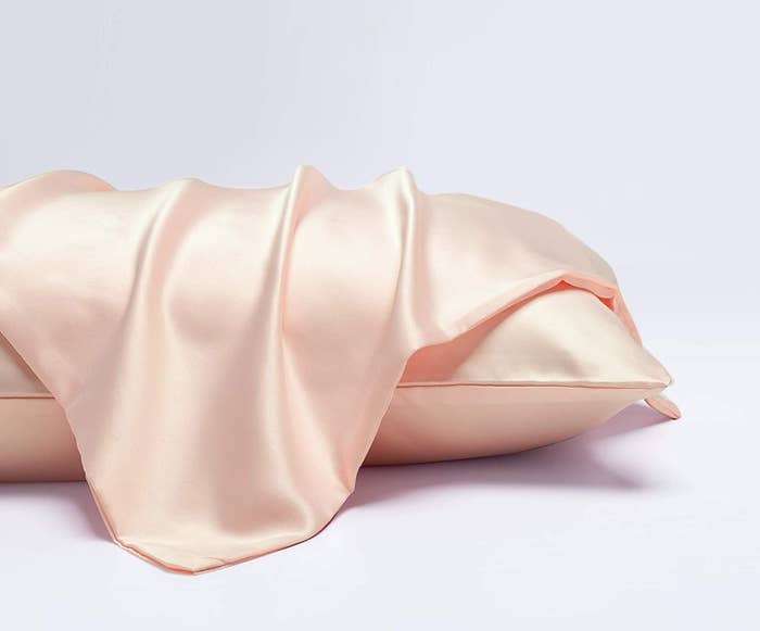 The light pink pillowcase laying on a dressed pillow