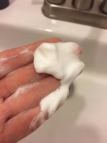 A reviewer's hand with the foamy cleanser inside