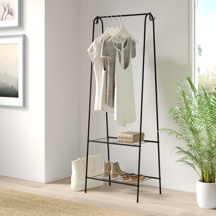 black steel garment rack with clothes hanging up and shoes on the bottom rack