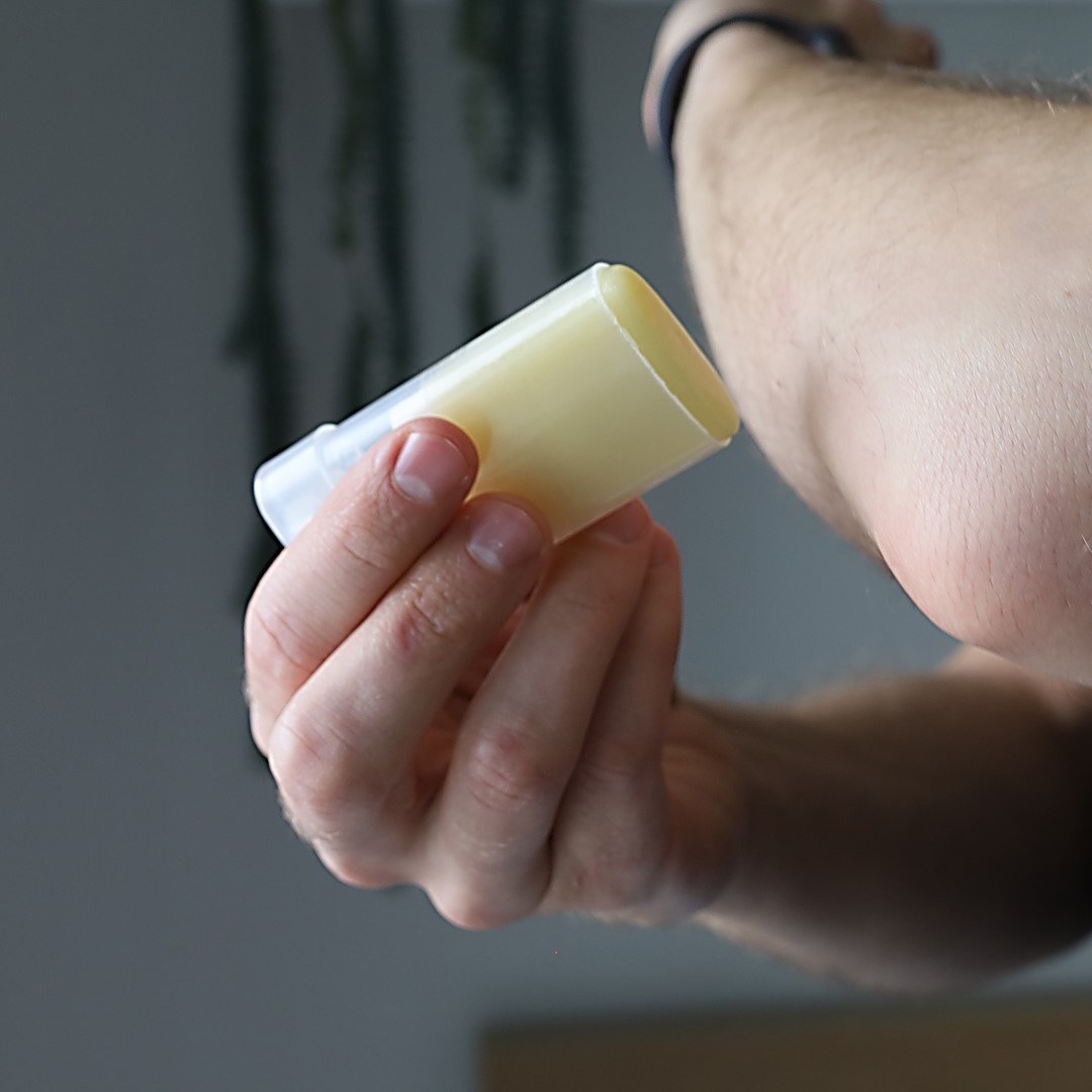 A person using the lotion stick on their elbow 