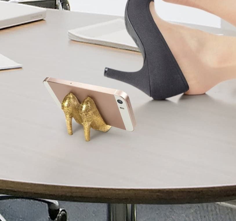 two small sparkly gold heels holding up a phone