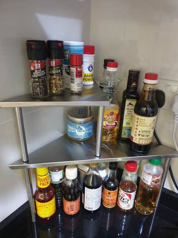 A reviewer's photo of the two-tier shelf holding pantry items like oil and spices