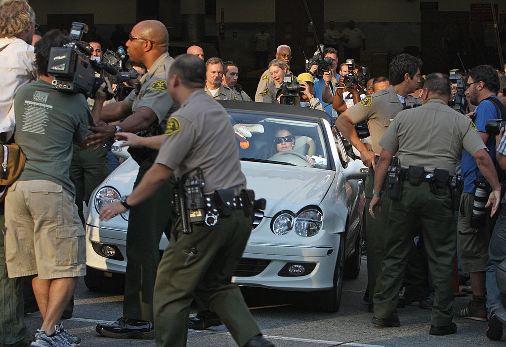 Britney attempting to drive her car as she swarmed by paparazzi and police officers trying to clear the way