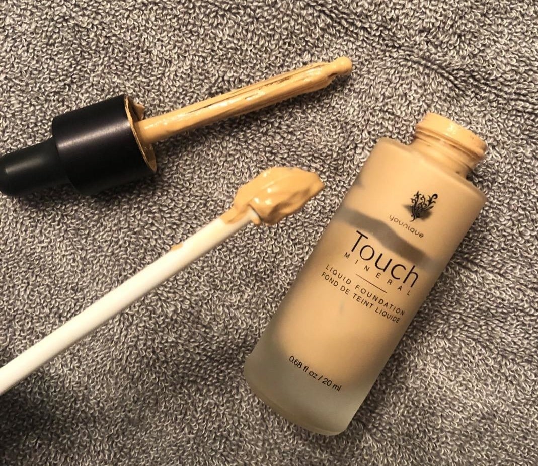 reviewer using the spatula to get foundation out of a bottle 
