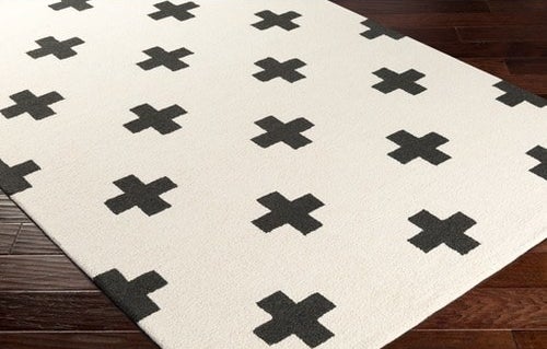 an off white rug with black cross designs on it 