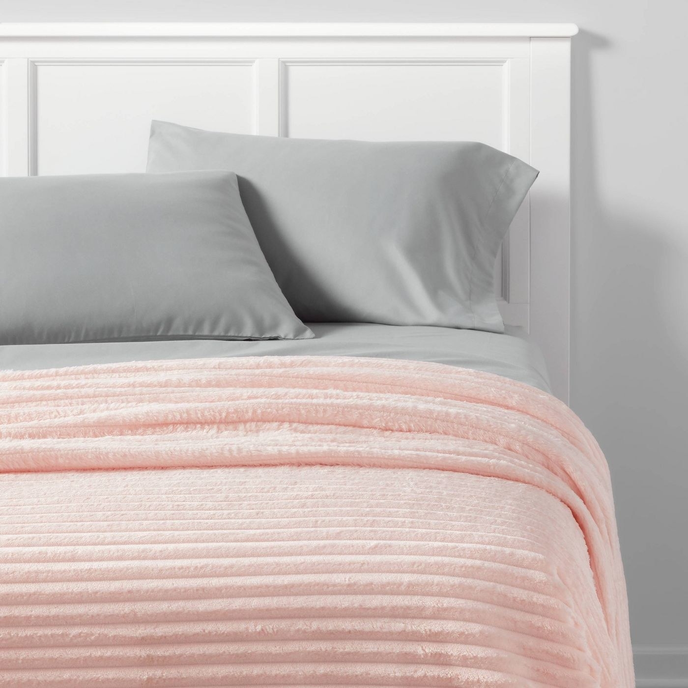 pink ribbed blanket on a bed