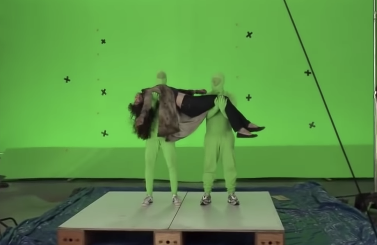two men in green screen morph suits hold Liv Tyler up