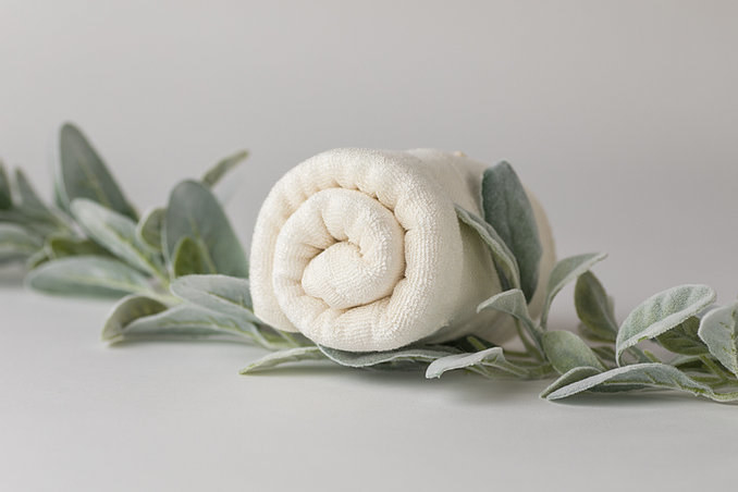 Wrapped towel on leaves on gray background