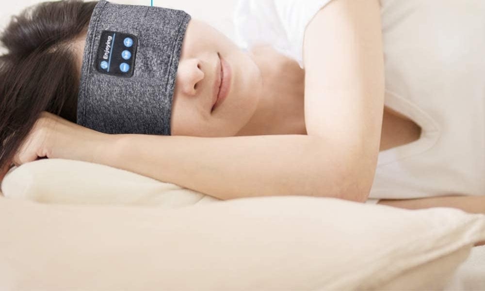 A person lying on their side while wearing the headband over their eyes 