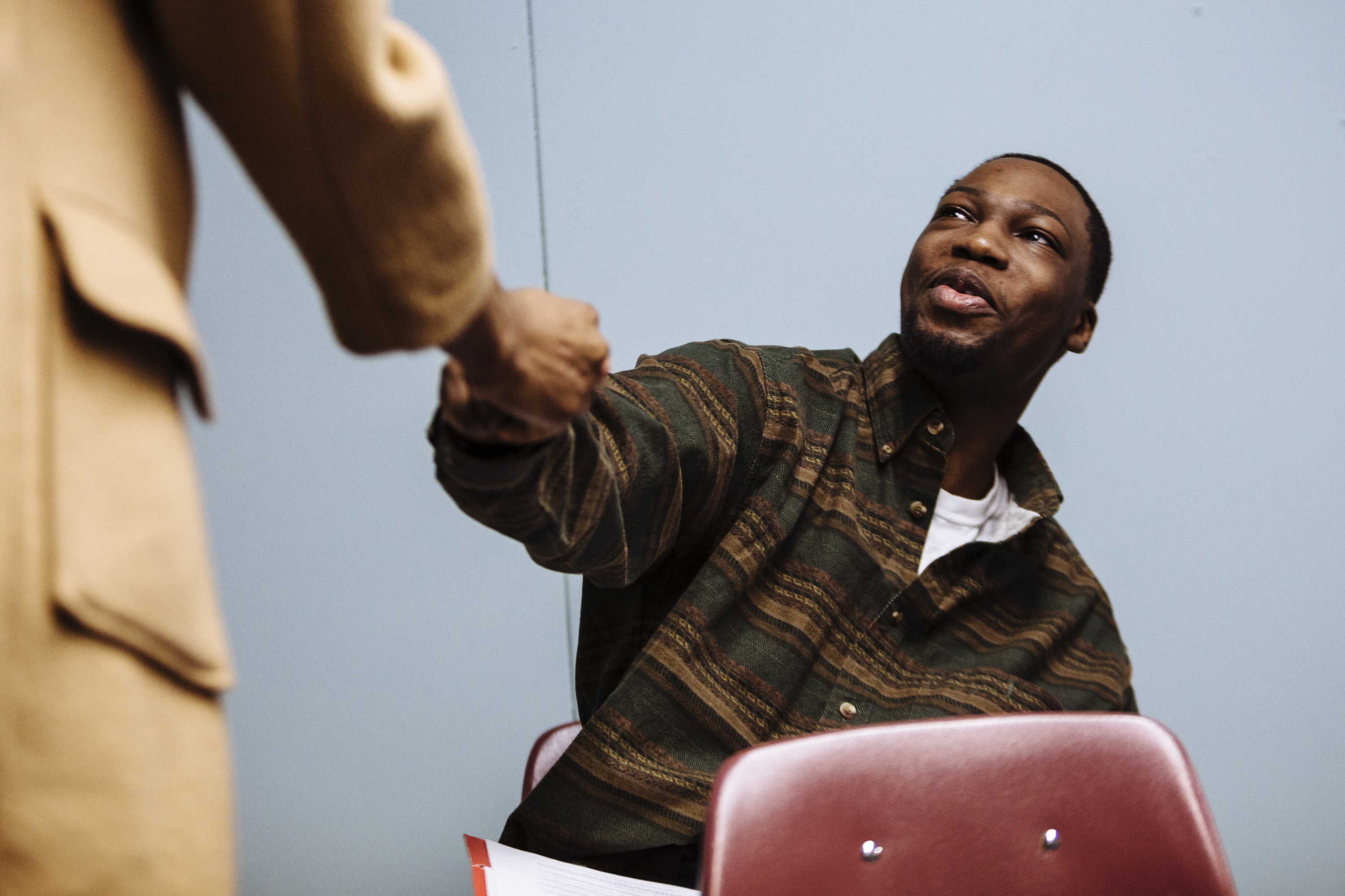 A seated man fist-bumps someone in a blazer at an employee training