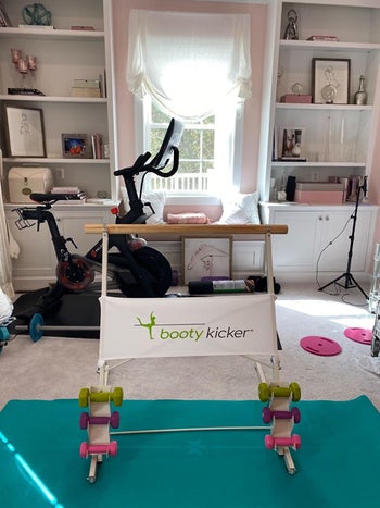 Booty Kicker bar with weights on the bottom in a reviewer's home gym