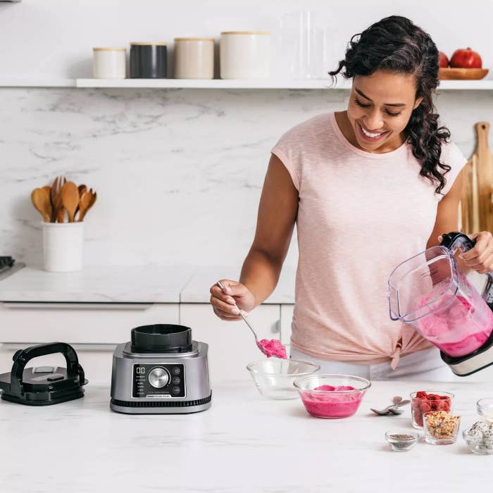 A model using the blender to make smoothies in a kitchen