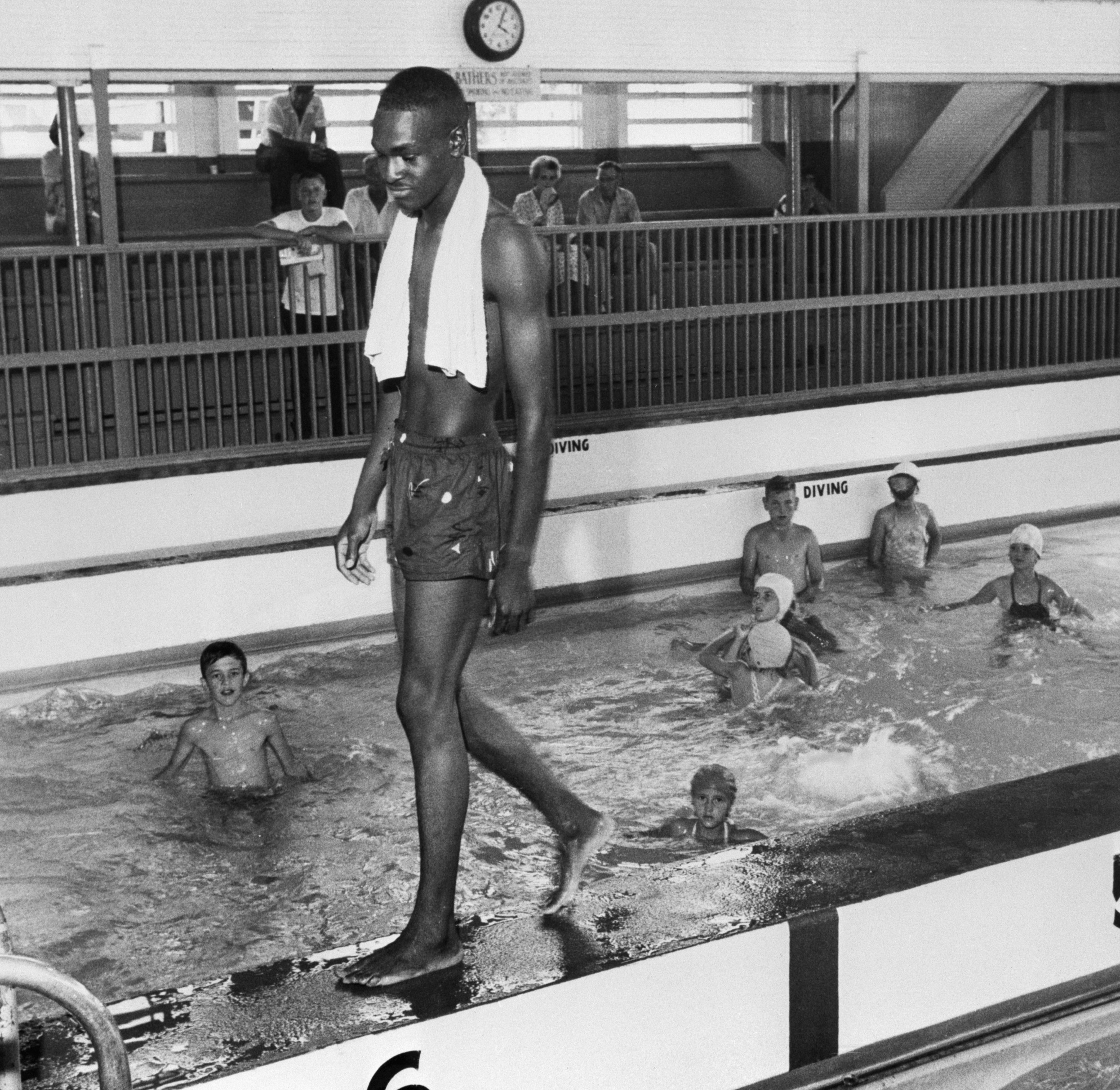 A Black teenager, David Isom, 19, walks along the edge of a white-only pool, breaking the color line in one of this city&#x27;s segregated public pools which resulted in officials closing the facility