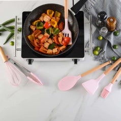 A set of pink silicone cutlery being used to cook