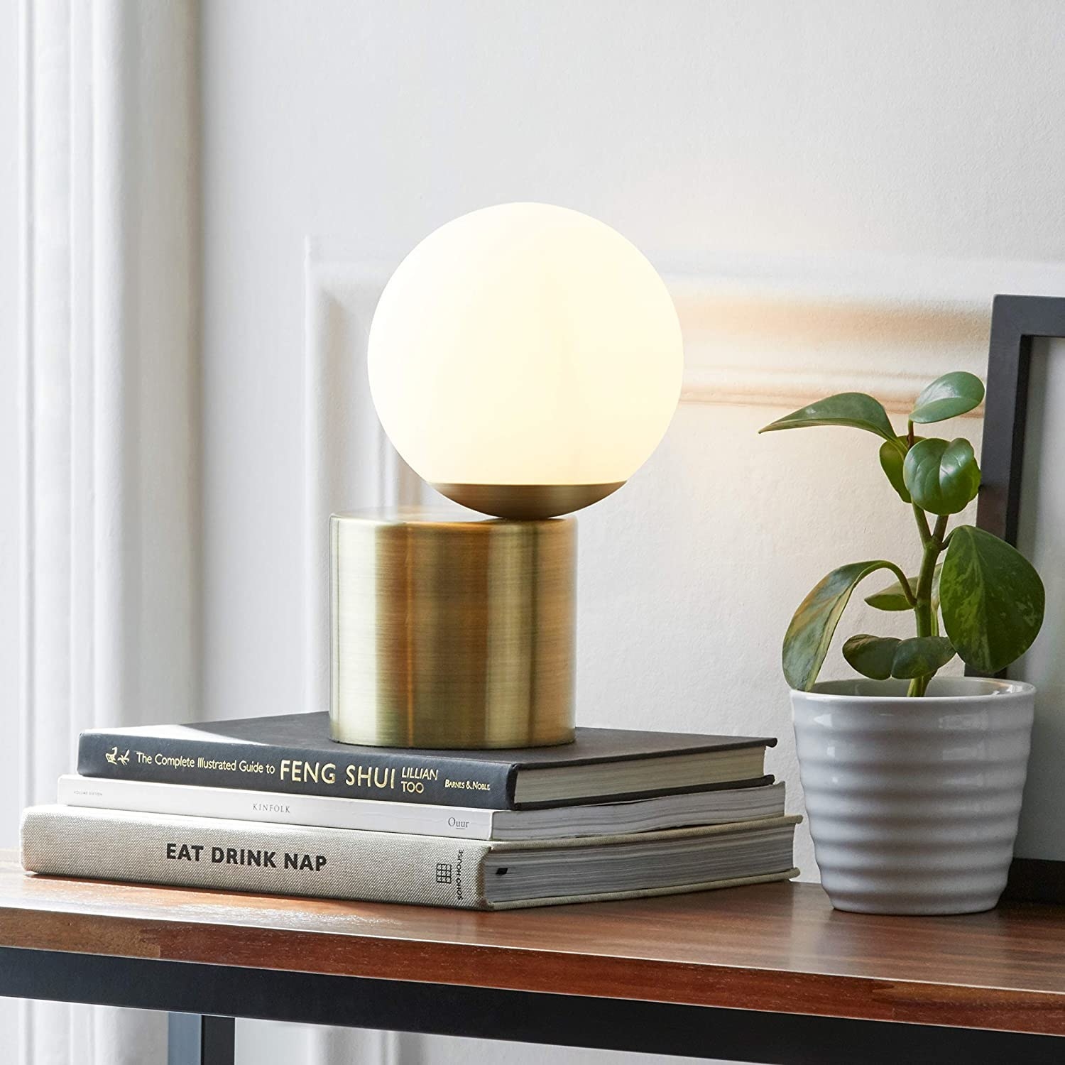 the gold rounded base lamp with round glass bulb off center from the base